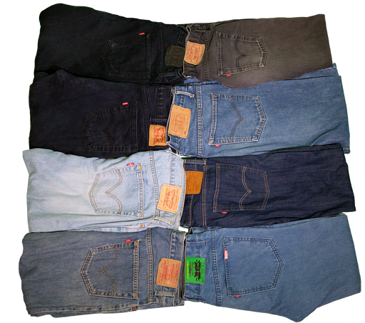 A variety of denim jeans in different shades and styles, neatly folded and stacked.