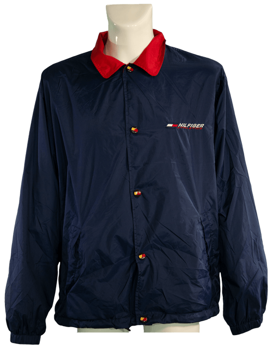 Navy blue windbreaker with red collar and button accents, featuring a small Hilfiger logo on chest.