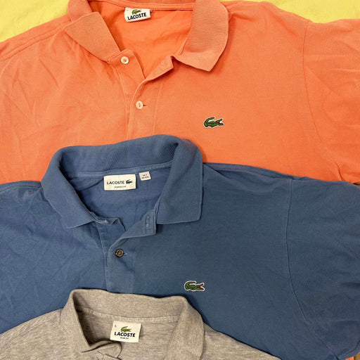 Vintage wholesale Lacoste polos from 70s, 80s, 90s, and 00s in orange, blue, and gray, showcasing classic vintage fashion