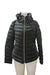 Black puffer jacket with hood on mannequin, featuring zipper closure and side pockets. Perfect for winter weather.