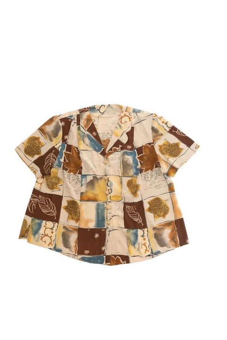 Short-sleeve button-up shirt with a colorful patchwork design featuring leaves and abstract patterns in earthy tones.