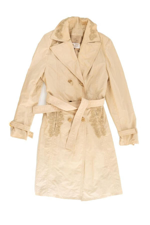 Beige double-breasted trench coat with belt and decorative detailing.